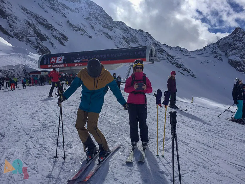 Skifahrende an der Bergstation vor der Felskulisse.